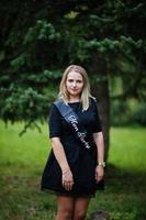 retrato de una hermosa chica vestida de negro en una despedida de soltera, posada en el parque. foto