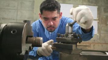 un lavoratore professionista asiatico maschio ingegnere industriale lavora in uniforme di sicurezza con strumenti di precisione per la lavorazione dei metalli, macchine per tornio meccanico e officina di pezzi di ricambio nella fabbrica di produzione dell'acciaio. video