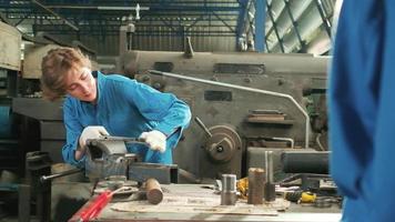 una joven ingeniera profesional de la industria trabaja con un uniforme de seguridad con herramientas de precisión de metalistería, tornos mecánicos y taller de piezas de repuesto en la fábrica de acero.