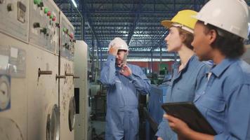 Multiracial professional industry engineer teams in hard hats and safety uniforms inspect machine control panels, check, and maintain at mechanical manufacture factory, electrical service occupations. video