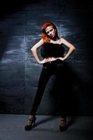 Fashion model red haired girl with originally make up like leopard predator against steel wall. Studio portrait. photo