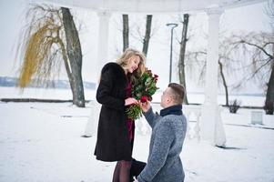 Married proposal with 101 rose at winter day. Loving couple. photo