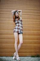 Amazing long legs with hig heels girl wear on hat against shutter. photo