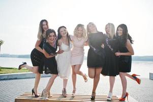 Group of 7 girls wear on black and 2 brides at hen party. photo