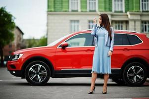 Outdoor photo of gorgeous woman posing near orange suv car.