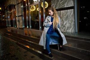 Girl with dreadlocks walking at night street of city. photo