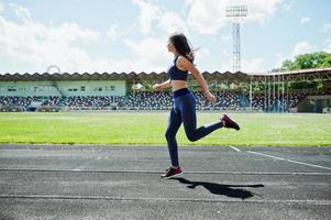 Portrait of a strong fit girl in sportswear running in the stadium. photo