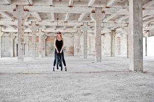 Red haired stylish girl in sunglasses wear in black, against abadoned place. photo