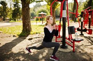 Young girl has the training and doing exercise outdoors on street simulators. Sport, fitness, street workout concept. photo
