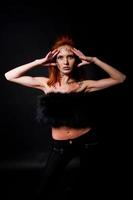 Fashion model red haired girl with originally make up like leopard predator isolated on black. Studio portrait.