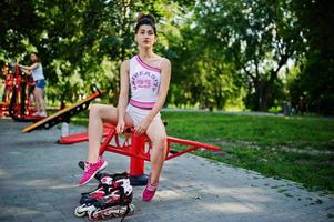 ropa de niña deportiva en pantalones cortos blancos y camisa haciendo ejercicios en simuladores al aire libre en el parque. foto