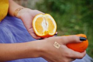 Two pieces of orange at in girl hands with black manicure. photo