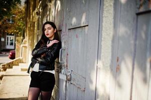 Stylish brunette girl wear on leather jacket and shorts posing at street. photo