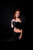 Fashion model red haired girl with originally make up like leopard predator isolated on black. Studio portrait.