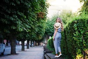retrato de una mujer joven fabulosa en general a rayas caminando sobre la barrera en el parque. foto