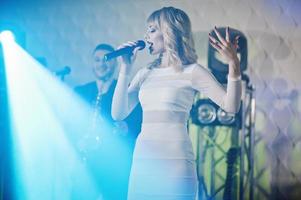 Musicial music live band performing on a stage with different lights. Beautiful blonde vocal singer girl. photo