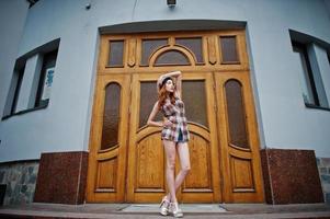 Amazing long legs with hig heels girl wear on hat posing against large wooden doors. photo