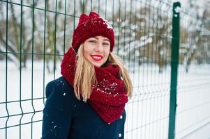 Blonde girl in red scarf and coat walking at park on winter day. photo