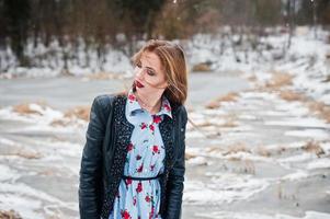 Stylish girl in leather jacket at winter day against frozen lake. photo