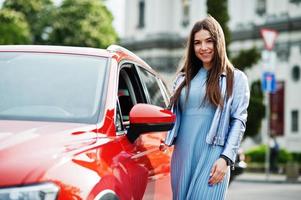 Outdoor photo of gorgeous woman posing near orange suv car.