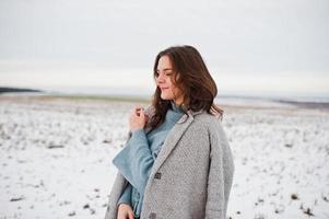 Gentle girl in gray coat against snow landscape. photo