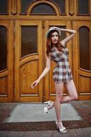 Amazing long legs with hig heels girl wear on hat posing against large wooden doors. photo