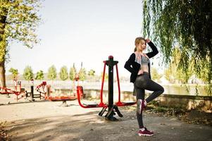 la joven tiene el entrenamiento y hace ejercicio al aire libre en simuladores callejeros. deporte, fitness, concepto de entrenamiento callejero. foto