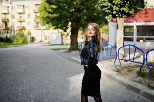 Elegant blonde girl wear on black leather jacket posing at streets of town. photo