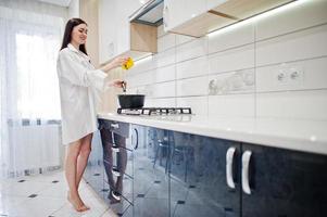 Brunette girl, wear at shirt and underwear cooking at the white kitchen. photo