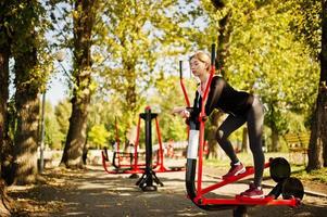 Young girl has the training and doing exercise outdoors on street simulators. Sport, fitness, street workout concept. photo