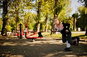 la joven tiene el entrenamiento y hace ejercicio al aire libre en simuladores callejeros. deporte, fitness, concepto de entrenamiento callejero. foto