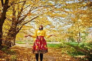 African american girl at yellow and red dress at golden autumn fall park. photo