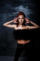 Fashion model red haired girl with originally make up like leopard predator against steel wall. Studio portrait. photo