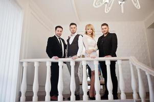 tres elegantes hombres barbudos bien vestidos con una chica rubia vestida de blanco posaron. banda de músicos o cantantes. foto