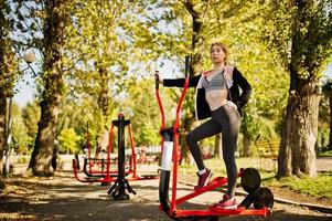 la joven tiene el entrenamiento y hace ejercicio al aire libre en simuladores callejeros. deporte, fitness, concepto de entrenamiento callejero. foto