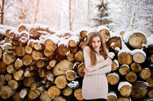 Beautiful brunette girl in winter warm clothing. Model on winter sweater near stump. photo