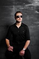 Studio portrait of stylish man wear on black shirt and glasses against steel wall. photo