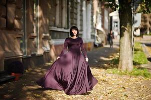 mujer morena adulta en vestido violeta sobre fondo de otoño. foto