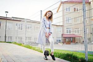 Stylish curly blonde model girl wear on white posing against fence. photo