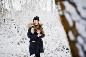 hermosa chica morena en ropa de abrigo de invierno. modelo con chaqueta de invierno y sombrero negro. foto