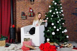 Cute girl wear on warm sweaters, black pants against new year tree with christmas decoration at studio. photo