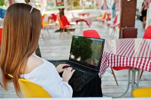 retrato de una fuerte y exitosa mujer de negocios independiente que usa ropa informal elegante y gafas que trabajan en una laptop en un café. foto