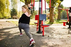 la joven tiene el entrenamiento y hace ejercicio al aire libre en simuladores callejeros. deporte, fitness, concepto de entrenamiento callejero. foto