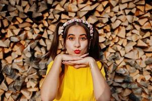 jovencita divertida con maquillaje brillante, vestida con camisa amarilla y corona sobre fondo de madera. foto