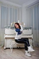 Girl wear warm sweater background piano with candles on studio. Happy new year winter holidays concept. photo