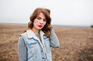 retrato de niña rizada morena con chaqueta de jeans en el campo. foto