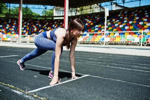 Portrait of a strong fit girl in sportswear running in the stadium. photo