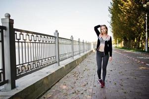 Young girl has the training and doing exercise outdoors. Sport, fitness, street workout concept. photo