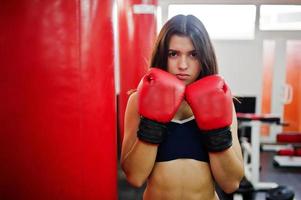 Young beautiful woman, wear on boxing gloves doing exercises and working hard in gym and enjoying her training process. photo