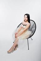 Portrait of brunette girl on beige dress with chair isolated on white. photo